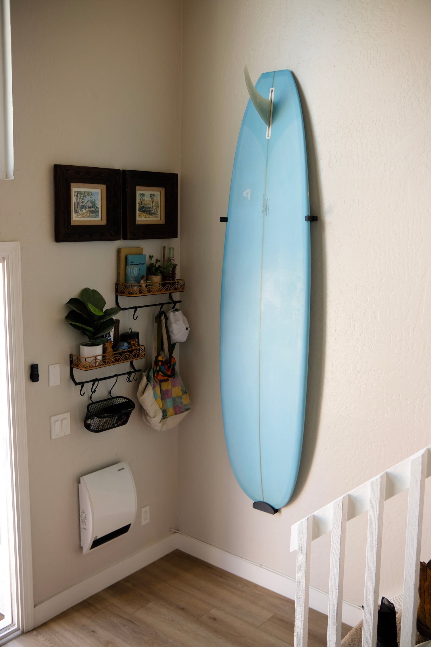 Longboard surfboard mounted vertically on a white wall using TrueRack surfboard mount.
