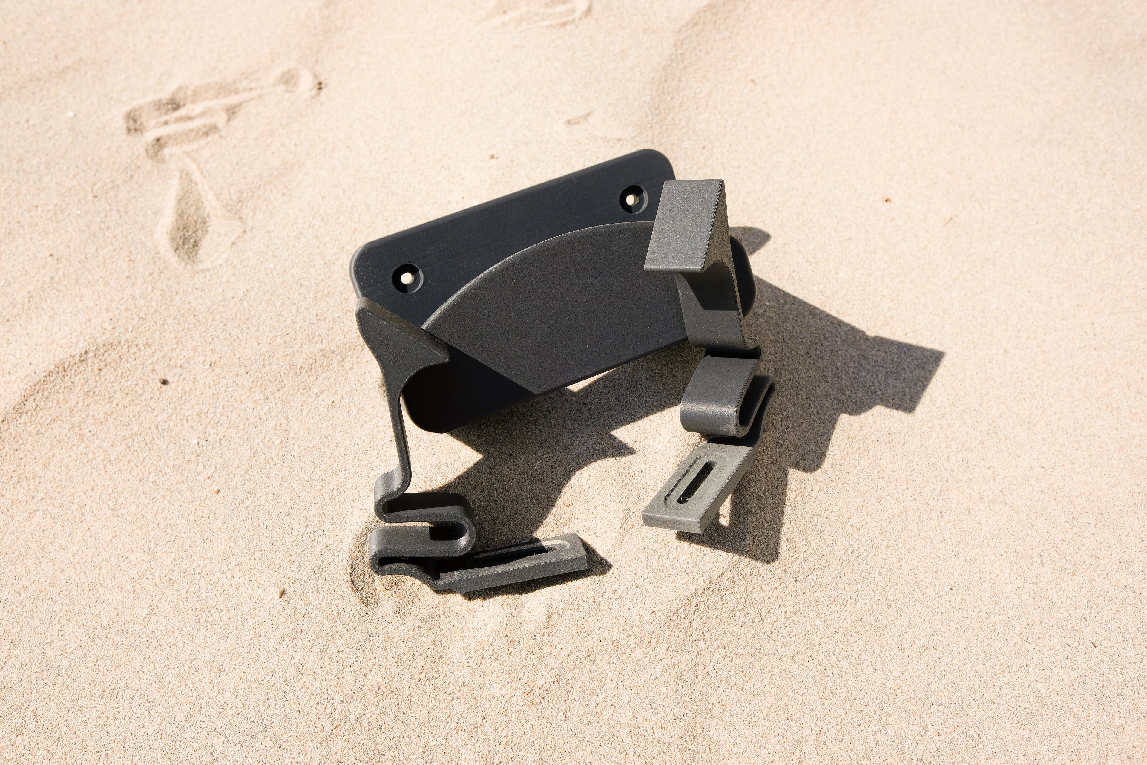 Close-up of TrueRack surfboard mount installed in sand, showing the durable base and clip design.